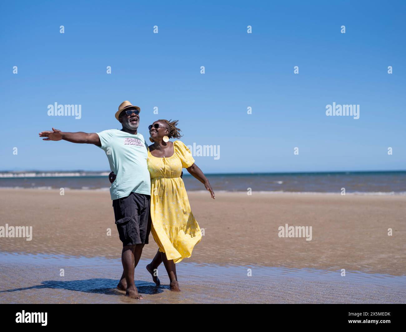 Älteres Paar zu Fuß am Strand Stockfoto