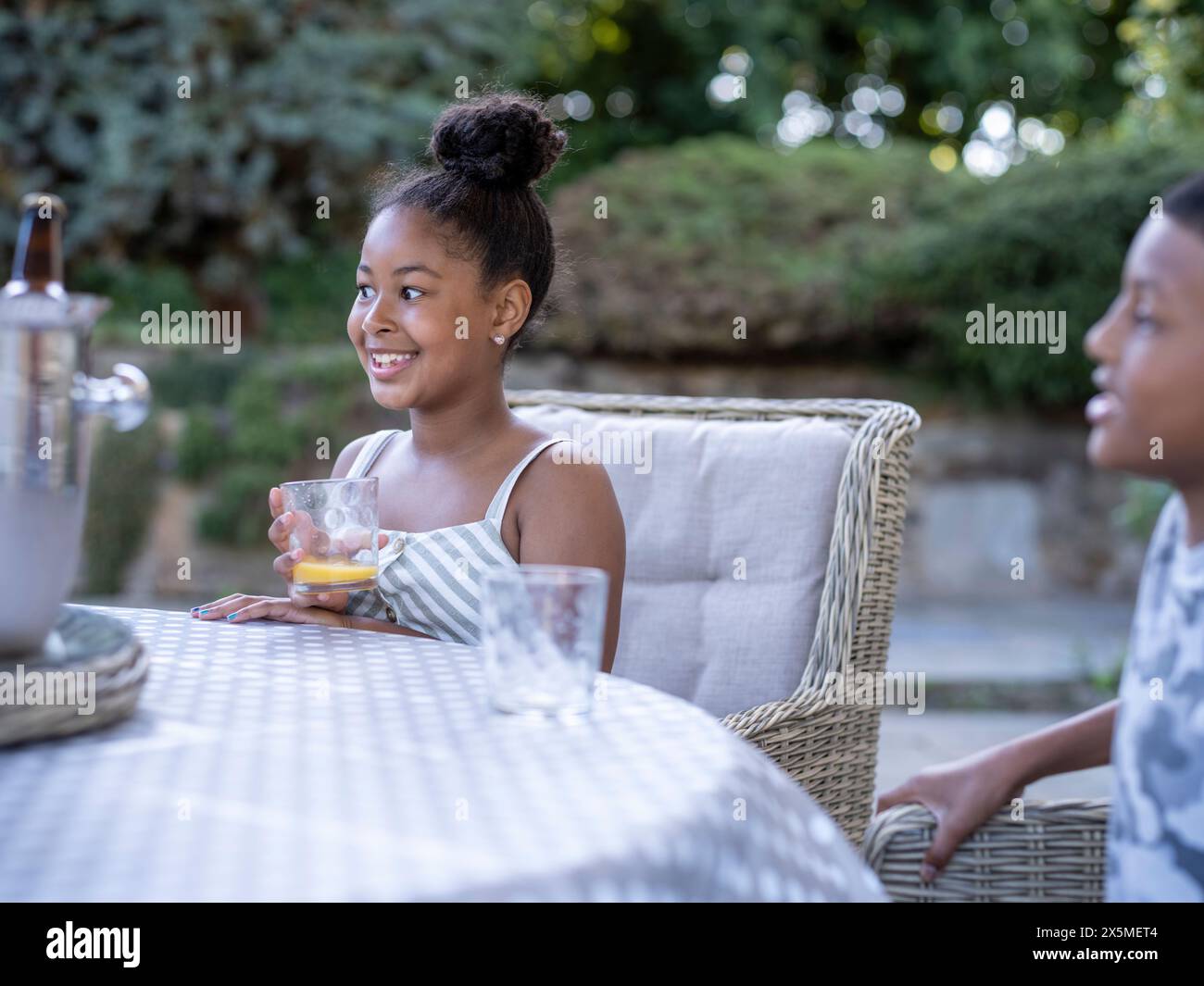 Geschwister (8-9, 10-11) sitzen am Tisch und trinken Saft Stockfoto