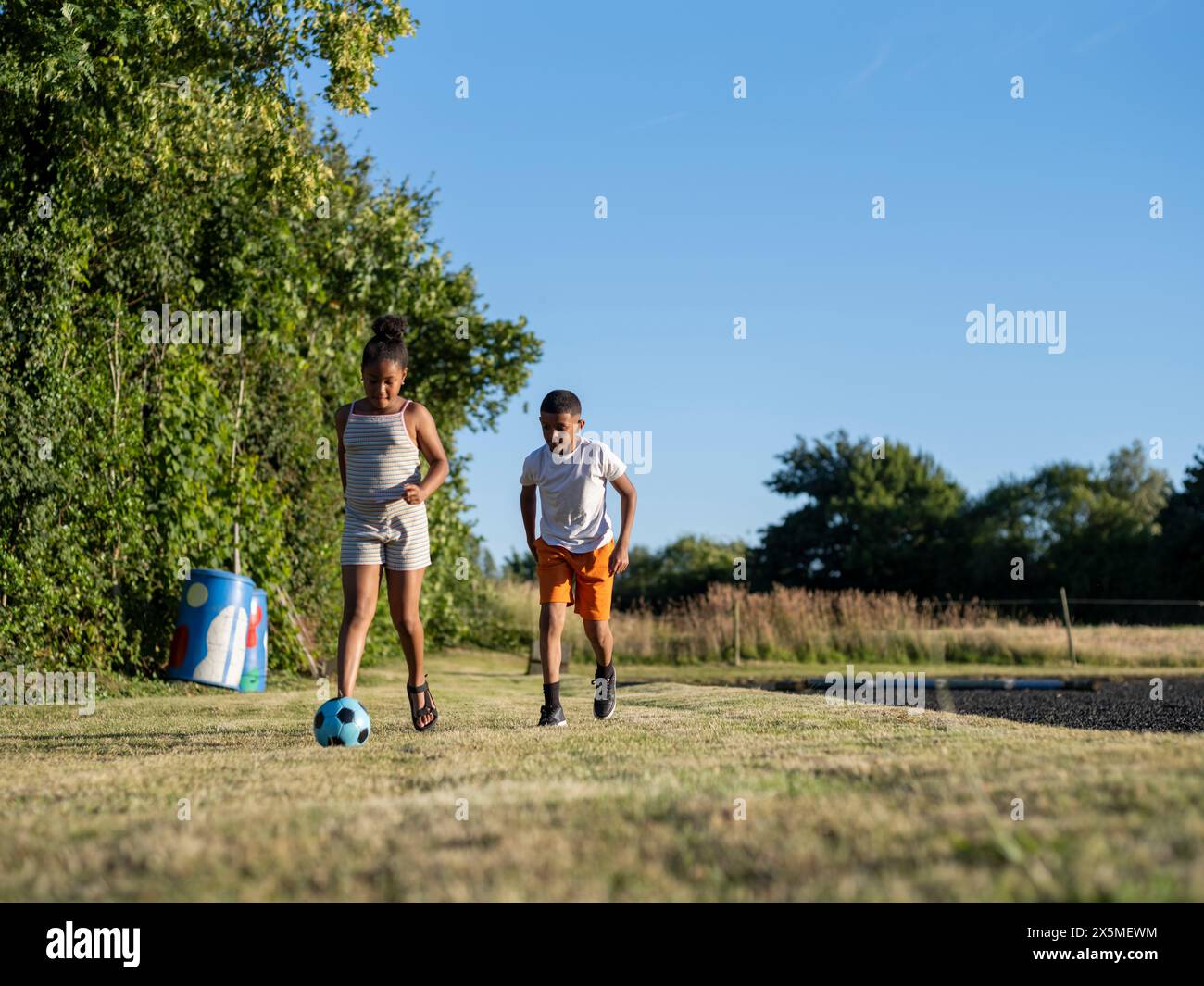 Geschwister (8-9, 10-11) spielen Fußball Stockfoto