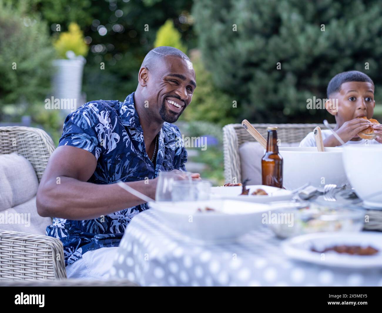 Vater und Sohn (10-11) essen draußen zu Abend Stockfoto