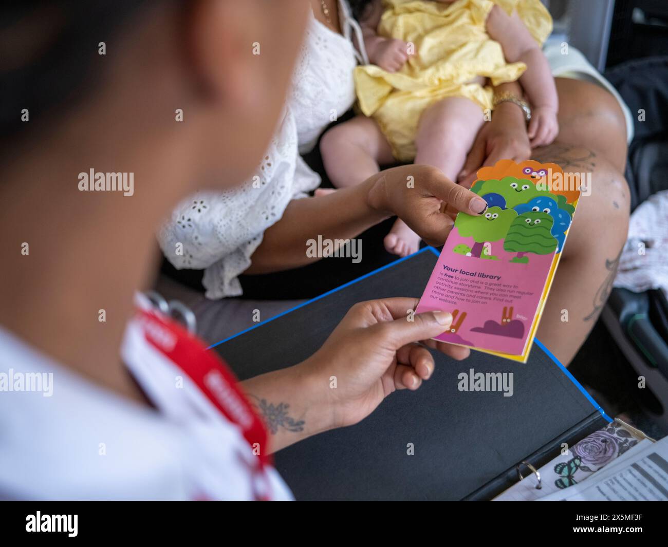 Schwester besucht Frau mit Baby Mädchen (2-5 Monate) zu Hause, um Broschüren zu geben Stockfoto