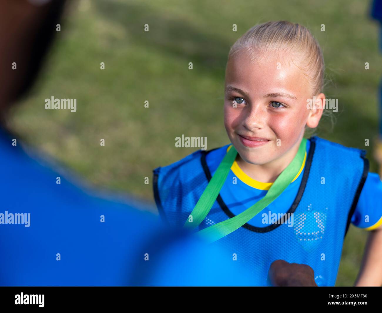 Mädchen (8-9) in Fußballuniform erhält Medaille vom Trainer Stockfoto