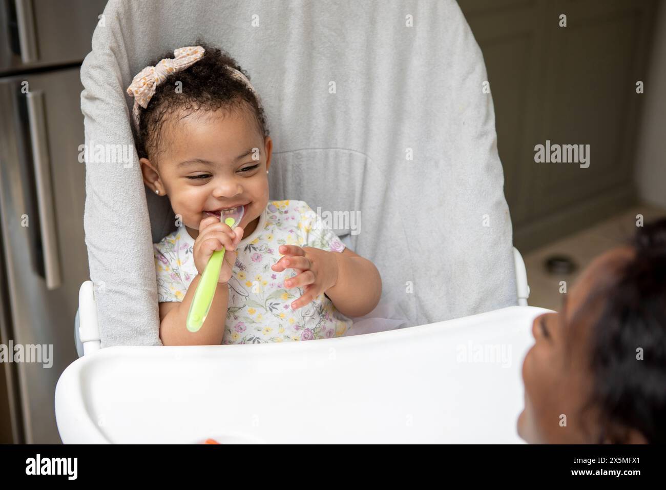 Baby Mädchen (12-17 Monate), das im Hochstuhl sitzt Stockfoto