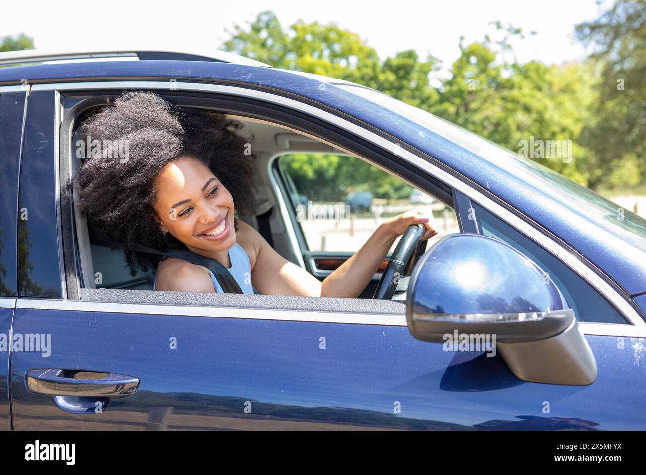 Eine junge Frau, die Auto fährt, sich aus dem Fenster beugt Stockfoto