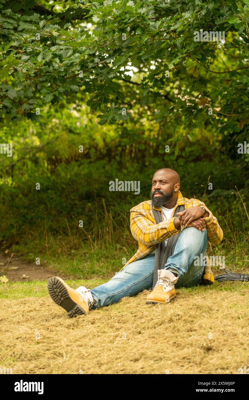 Mann, der sich im Herbst auf dem Rasen im Park entspannt Stockfoto