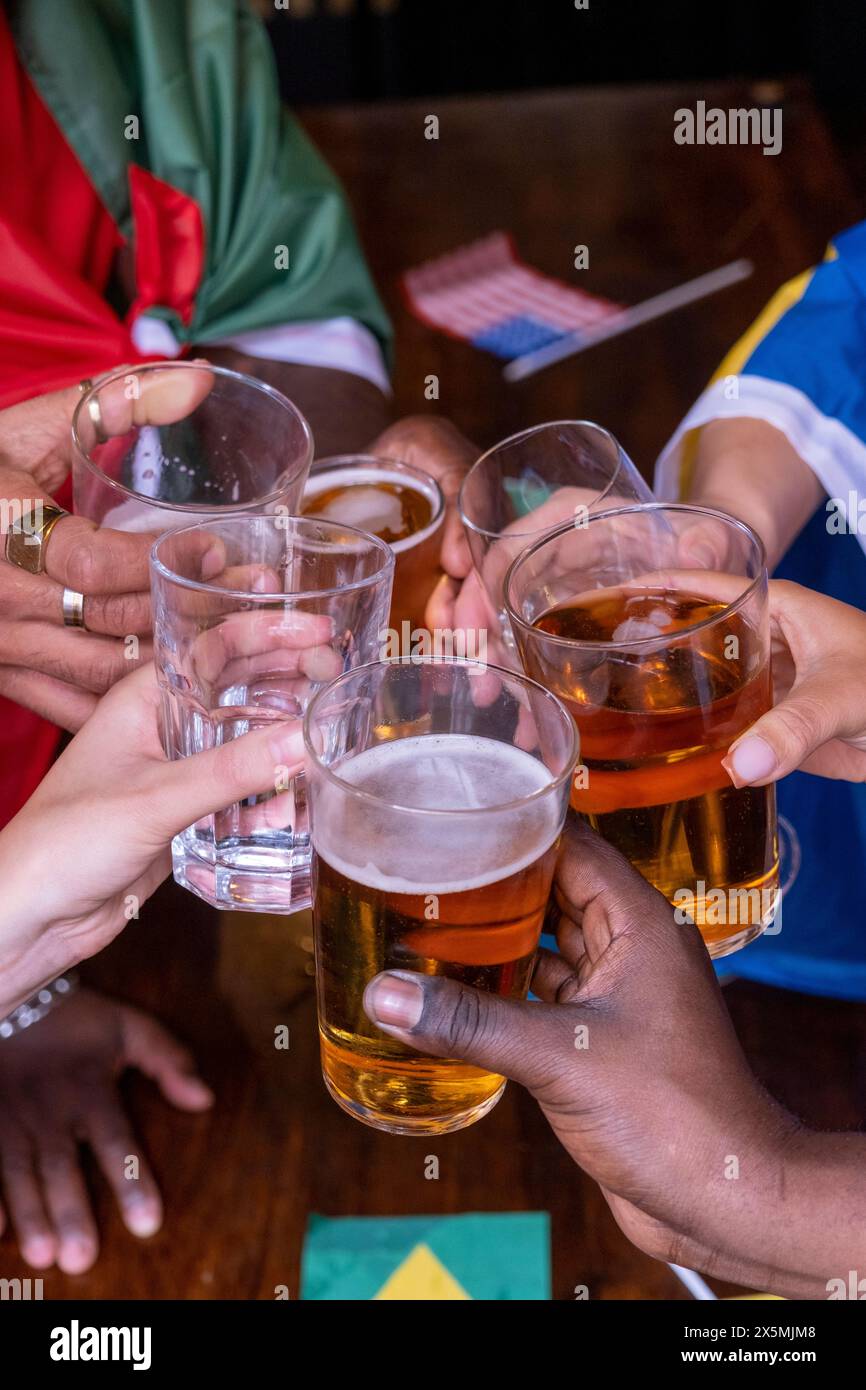 Freunde, die in Nationalflaggen gekleidet sind, um beim WM-Wettbewerb Bier zu trinken Stockfoto Freunde, die in Nationalflaggen gekleidet sind, um beim WM-Wettbewerb Bier zu trinken Stockfoto