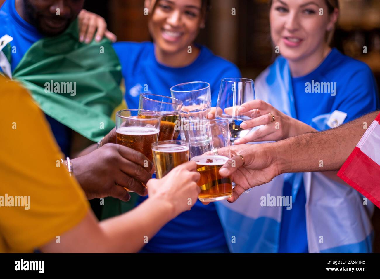 Freunde, die in Nationalflaggen gekleidet sind, um beim WM-Wettbewerb Bier zu trinken Stockfoto