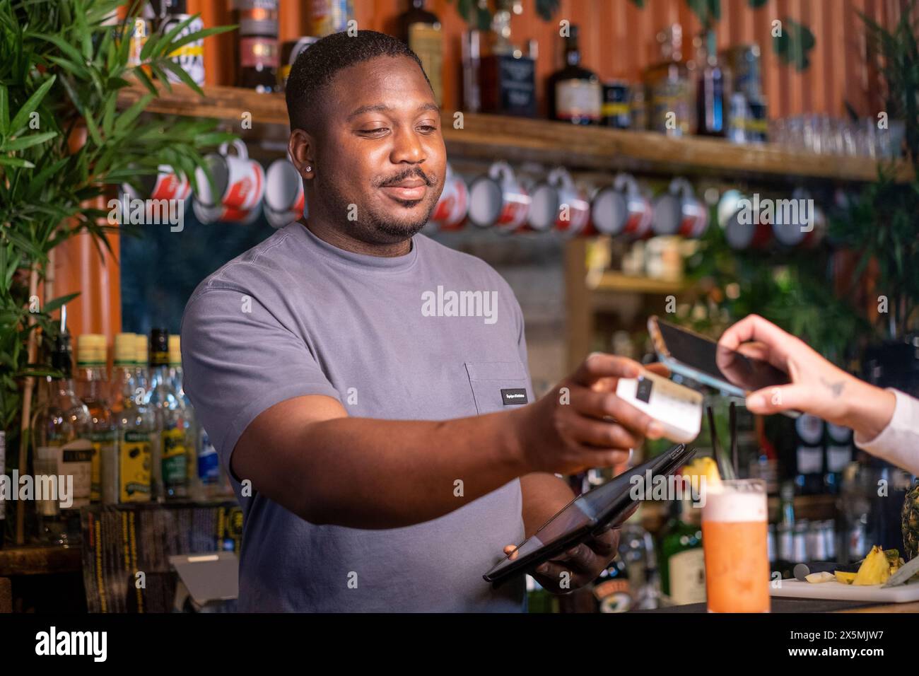 Barkeeper mit Kreditkartenleser und Tablet an der Bar, USUN wiek kobiety Stockfoto