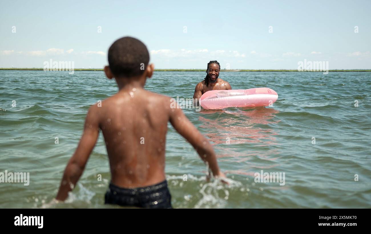 USA, Vater und Sohn spielen mit aufblasbarem Ring im Meer Stockfoto