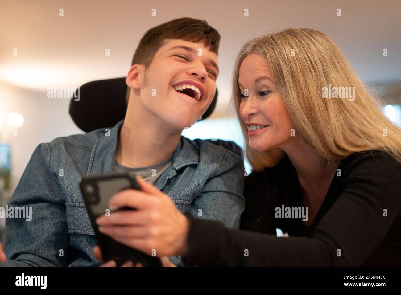 Mutter mit Smartphone und behindertem Sohn Stockfoto