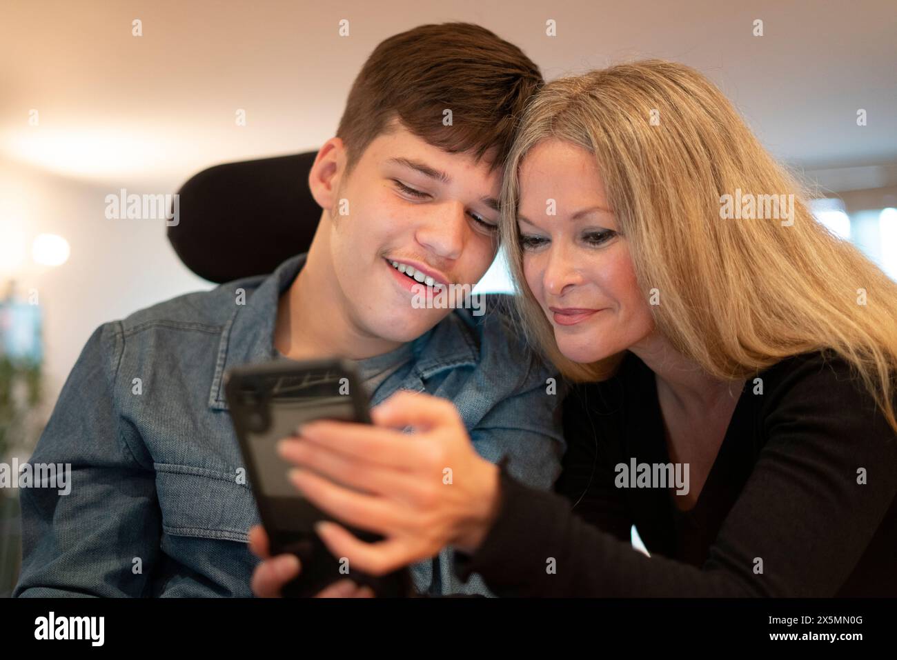 Mutter mit Smartphone und behindertem Sohn Stockfoto