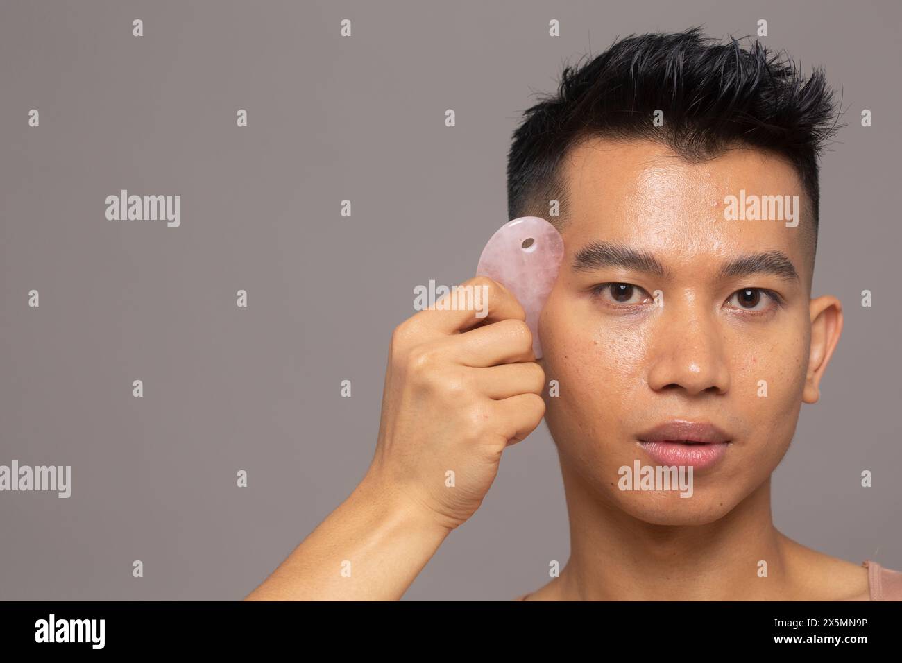 Studio-Porträt einer Person mit Rosenquarz guasha Stockfoto