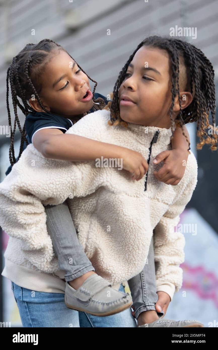 Porträt eines Jungen, der dem jüngeren Bruder Huckepack reitet Stockfoto