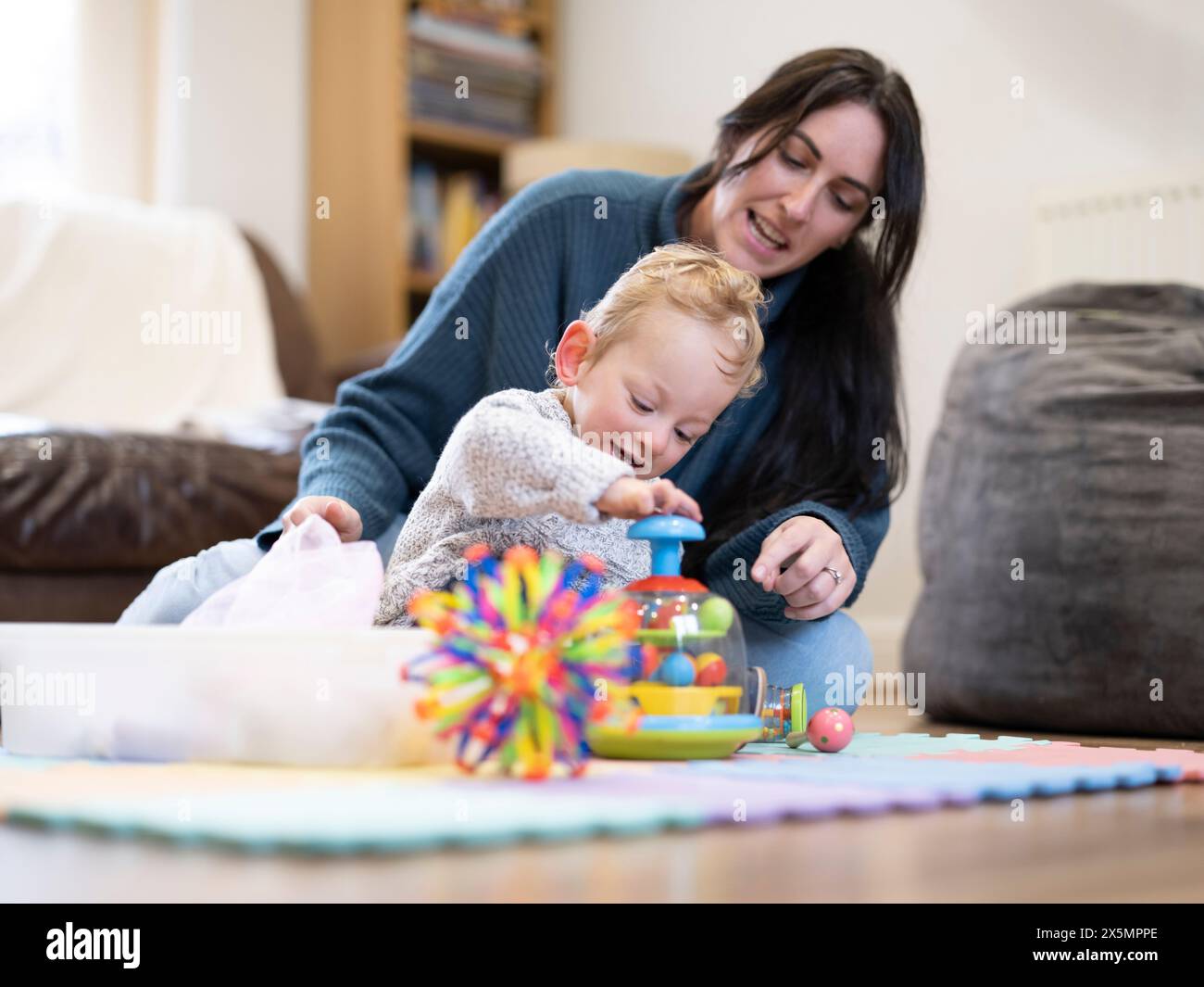Mutter, die den Sohn ansieht, der mit Spielzeug spielt Stockfoto