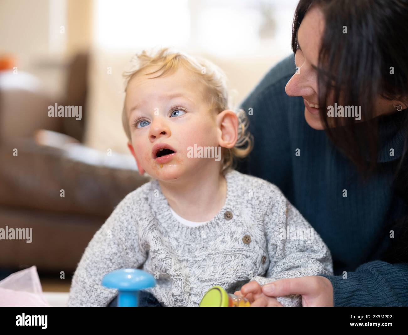 Lächelnde Mutter, die den Sohn mit Zerebralparese ansieht Stockfoto