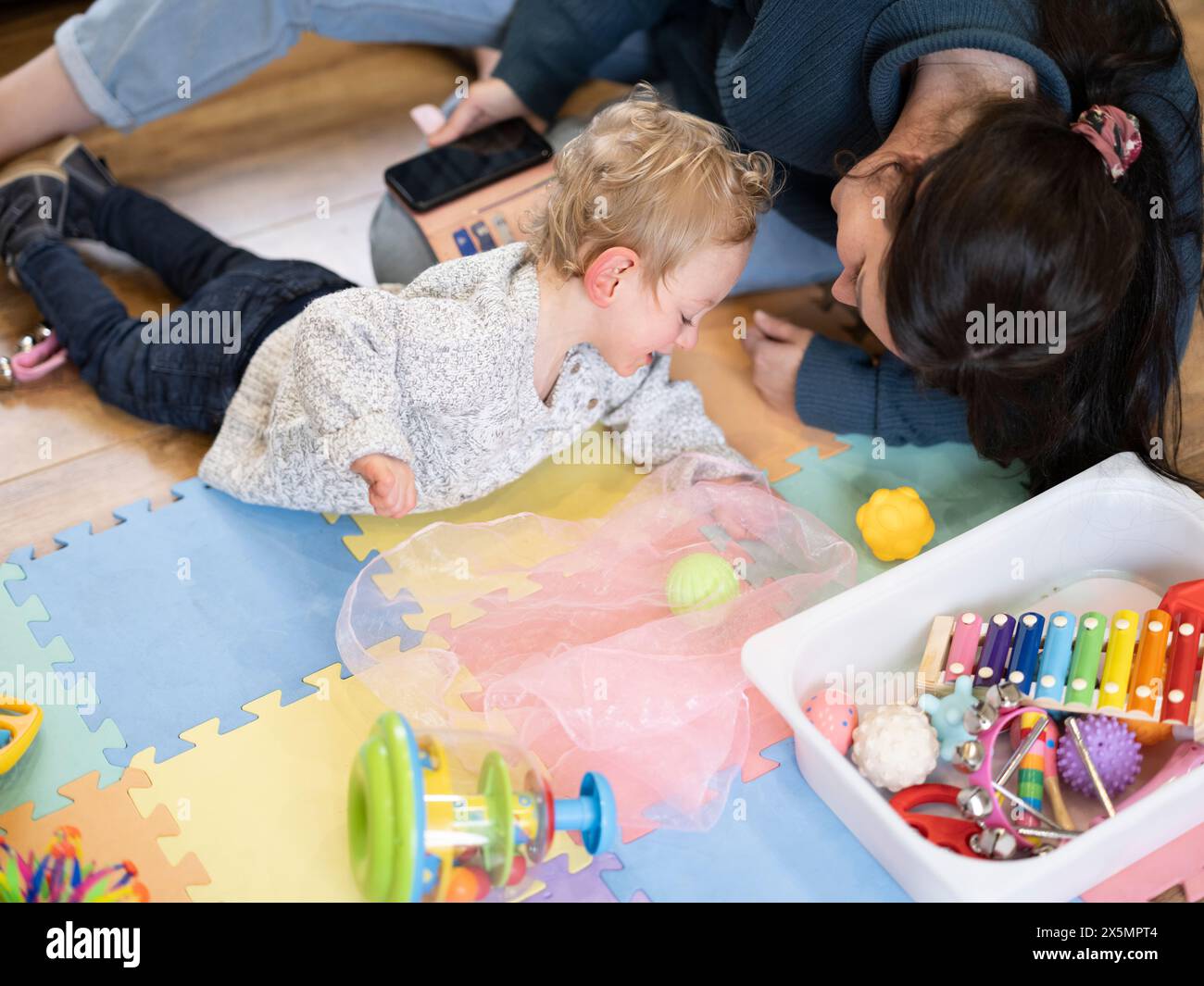 Mutter spielt zu Hause mit Sohn auf Matte Stockfoto