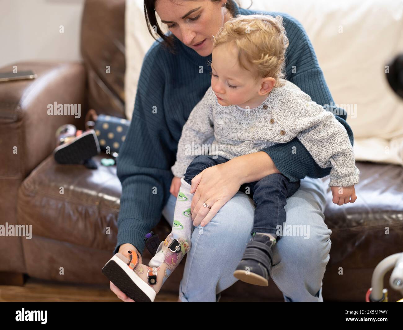 Mutter, die Beinspange auf den kleinen Sohn legt Stockfoto