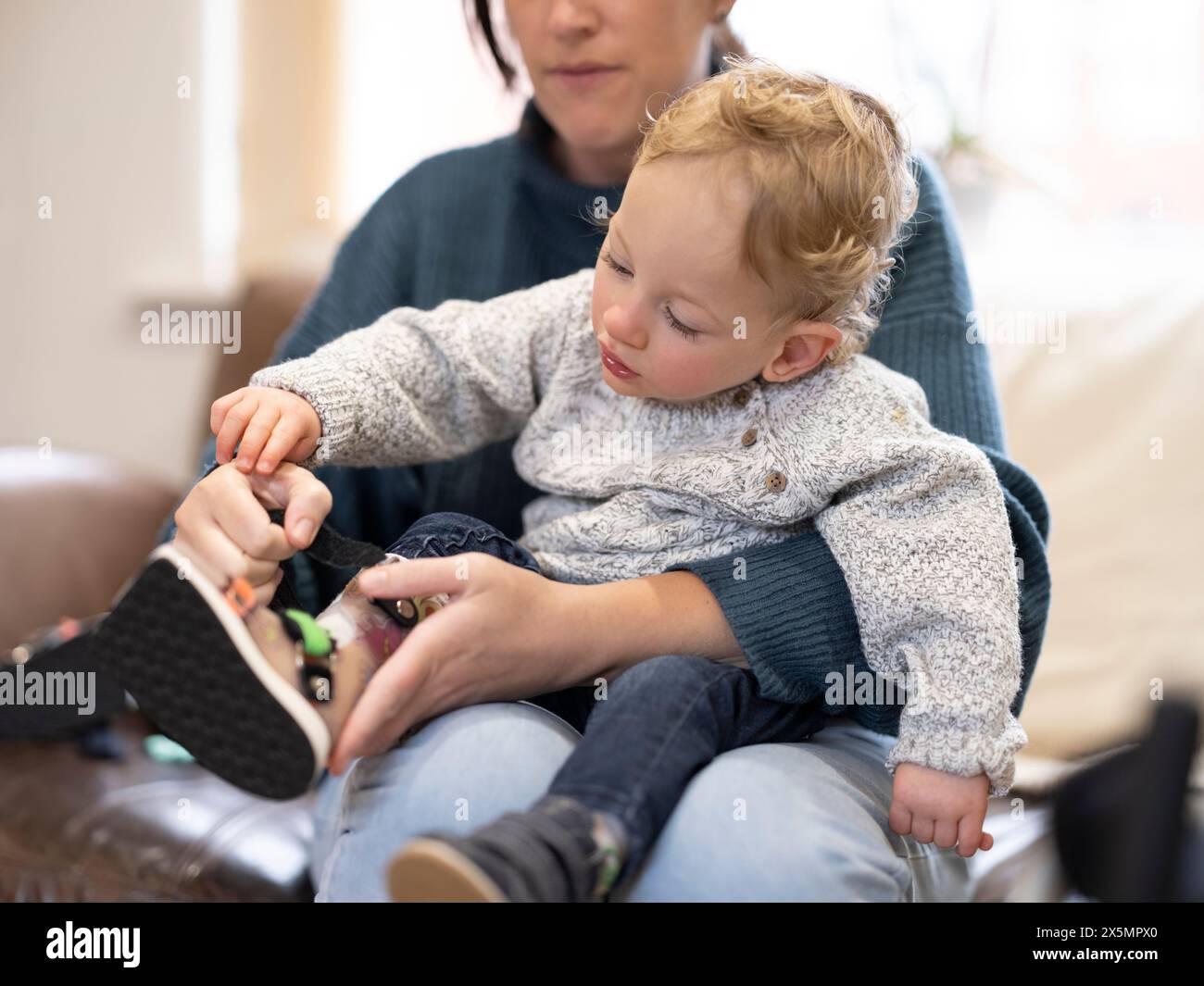 Mutter legt Beinstütze auf den Sohn Stockfoto