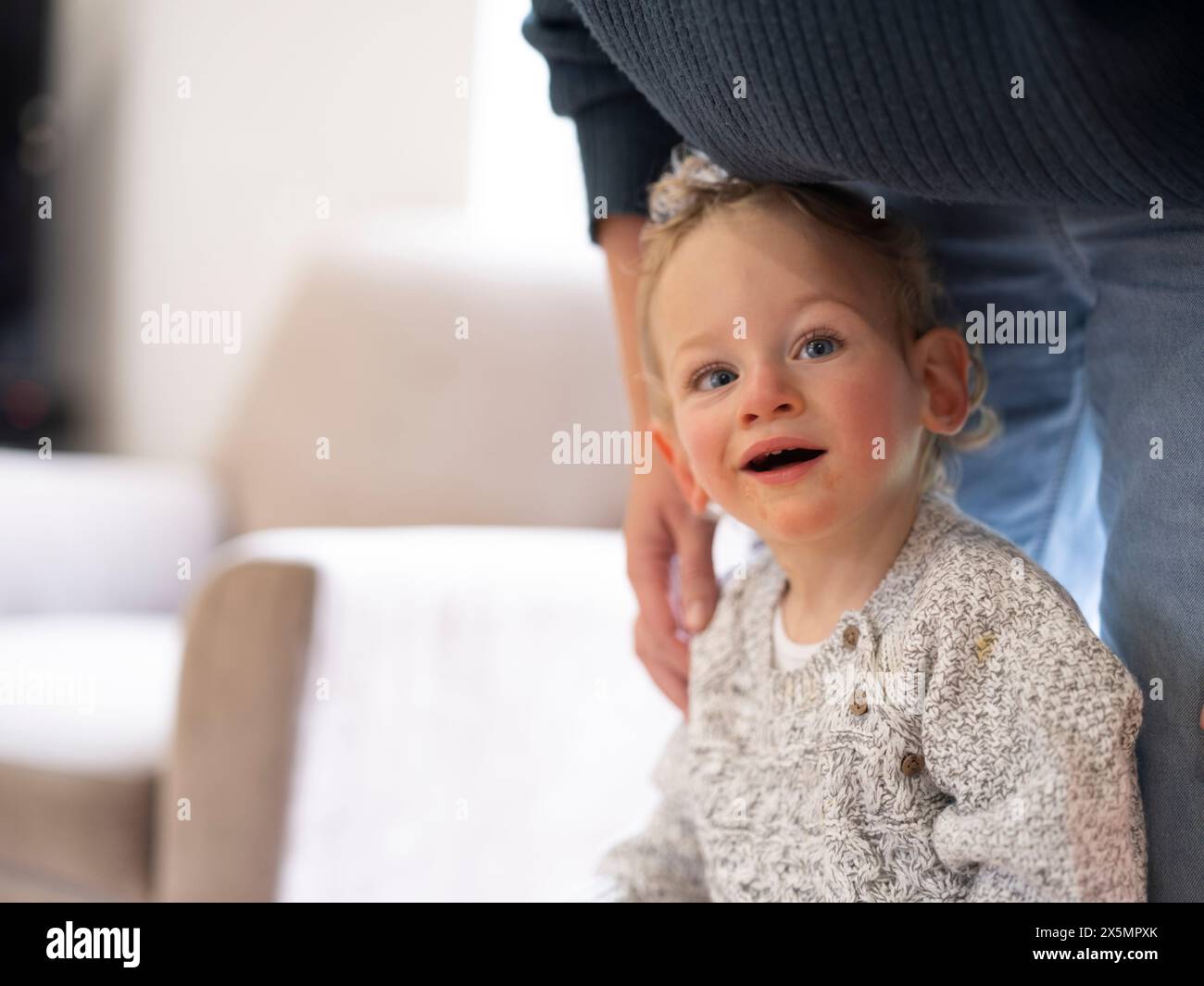 Der blonde Junge lehnt sich auf die Beine der Mutter und blickt in die Kamera Stockfoto