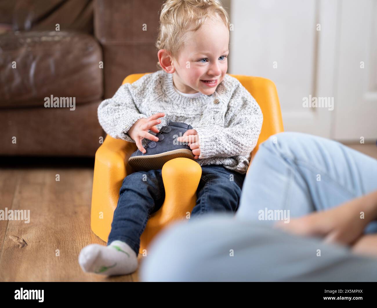 Blonder Junge mit Zerebralparese in Babyschale und Halteschuh Stockfoto