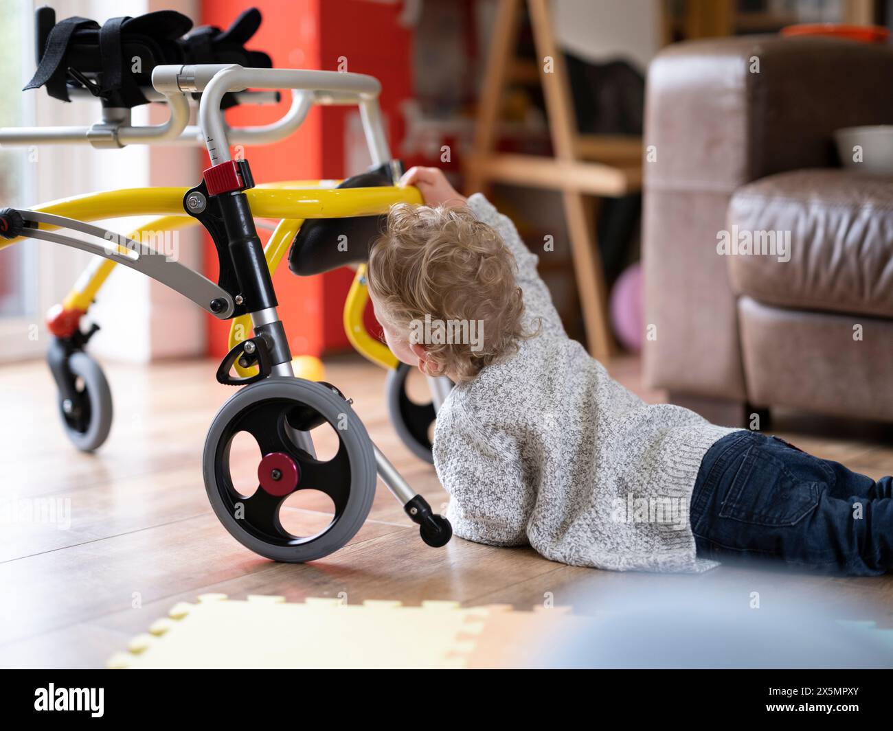 Junge, der vorne liegt und zum Gehhilfen greift Stockfoto