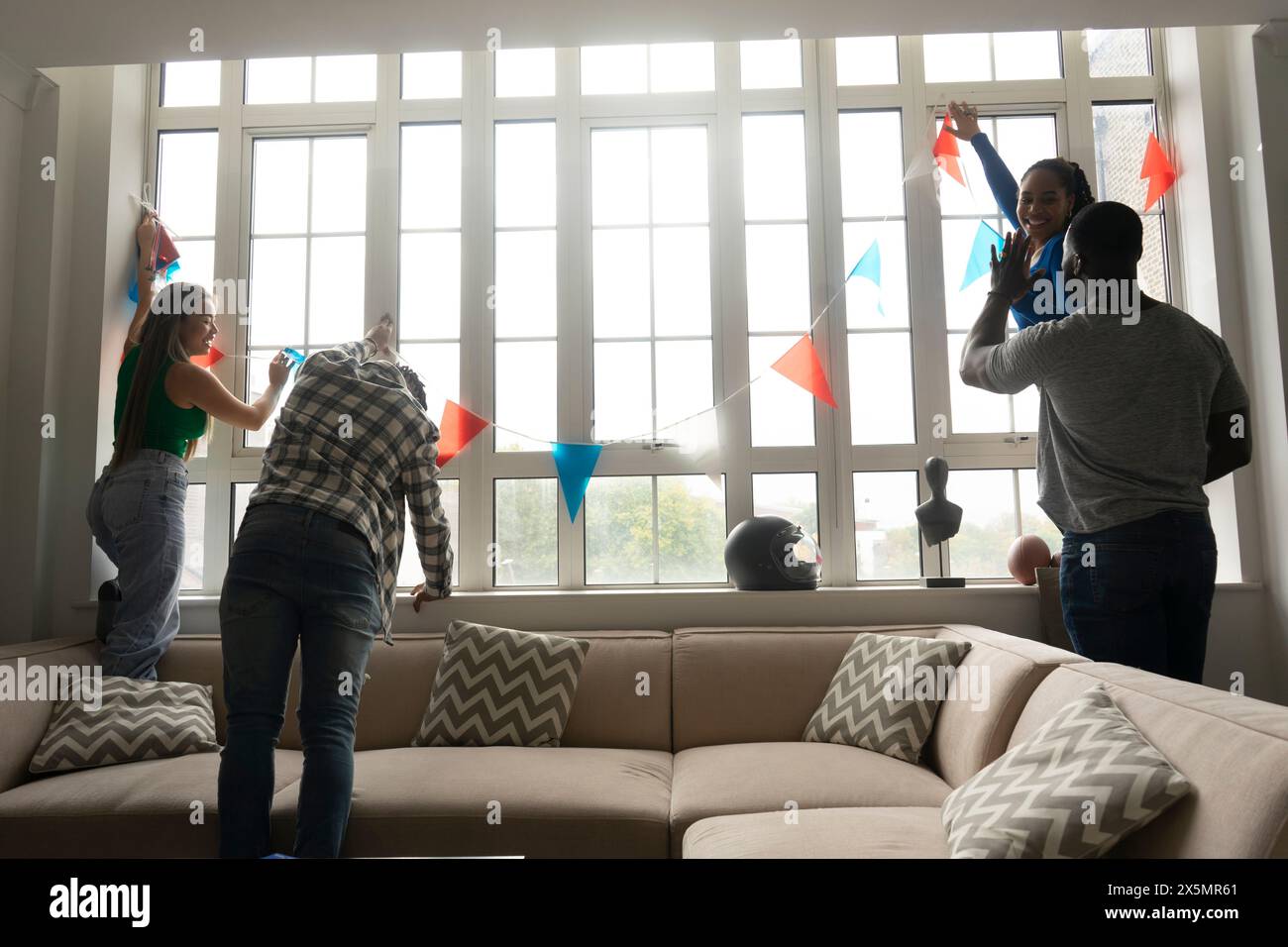 Freunde schmücken Fenster mit Wimpelfahnen Stockfoto