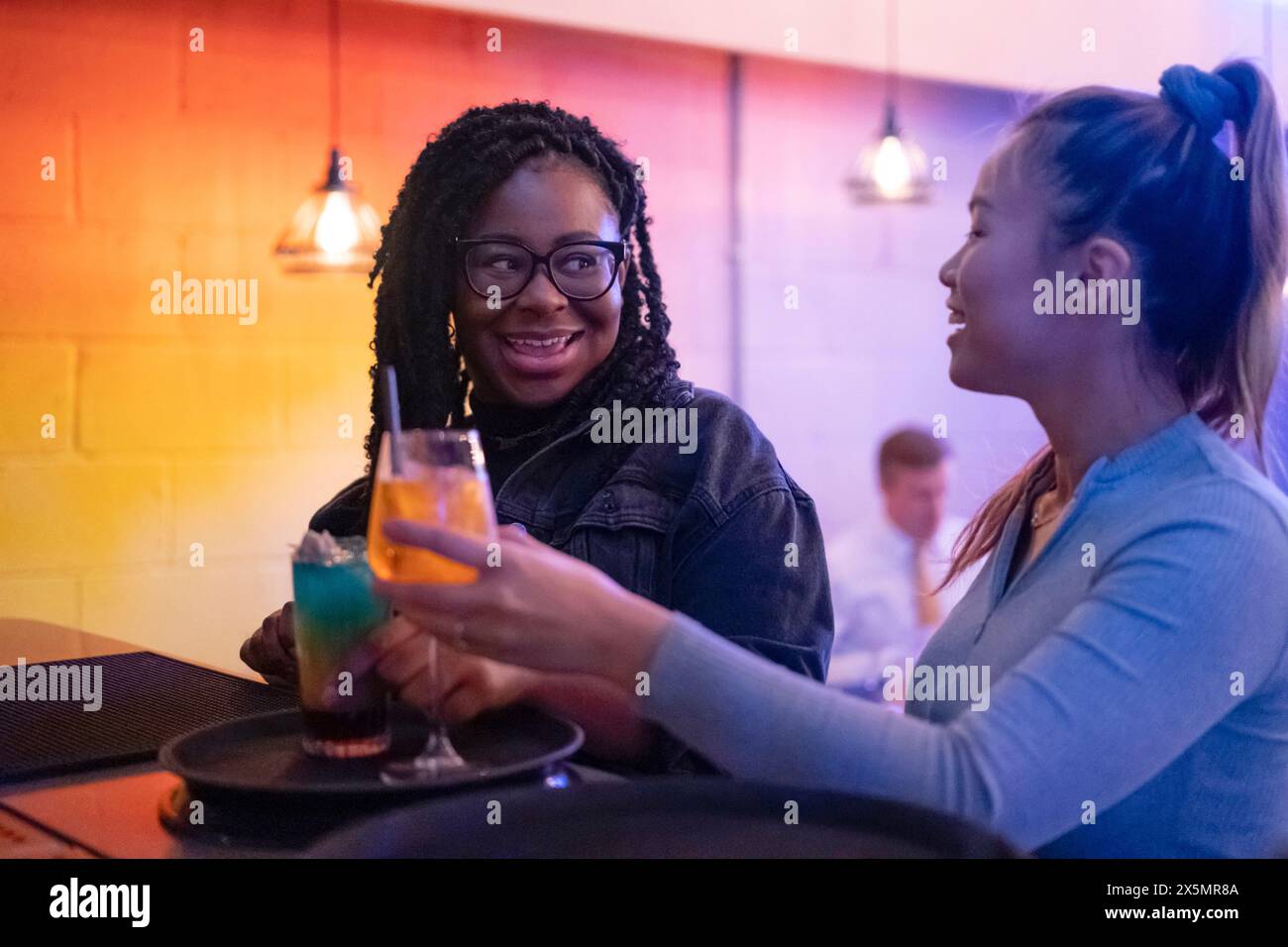 Weibliche Freunde trinken Cocktails an der Bar Stockfoto