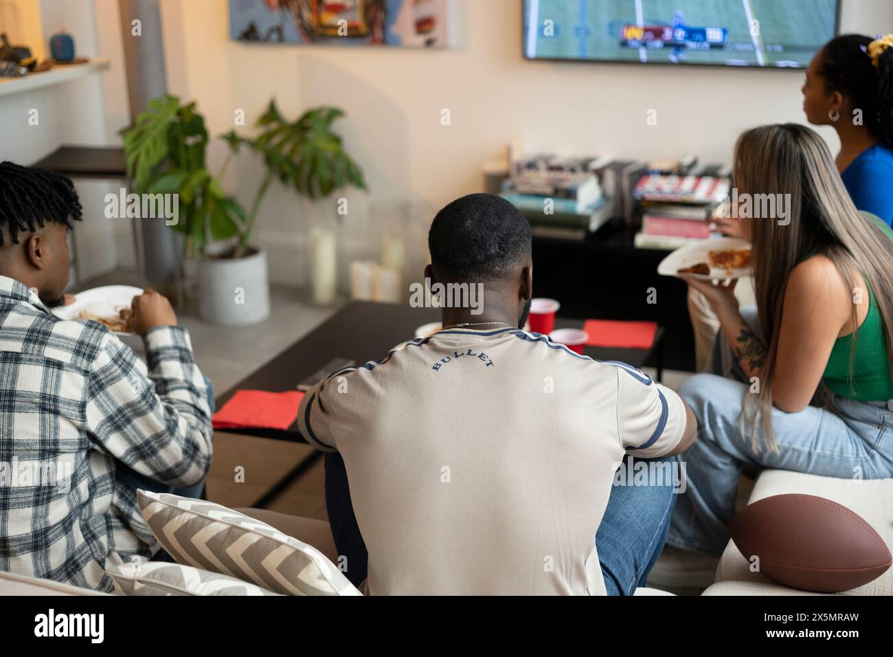 Freunde schauen American Football zu Hause im Fernsehen Stockfoto