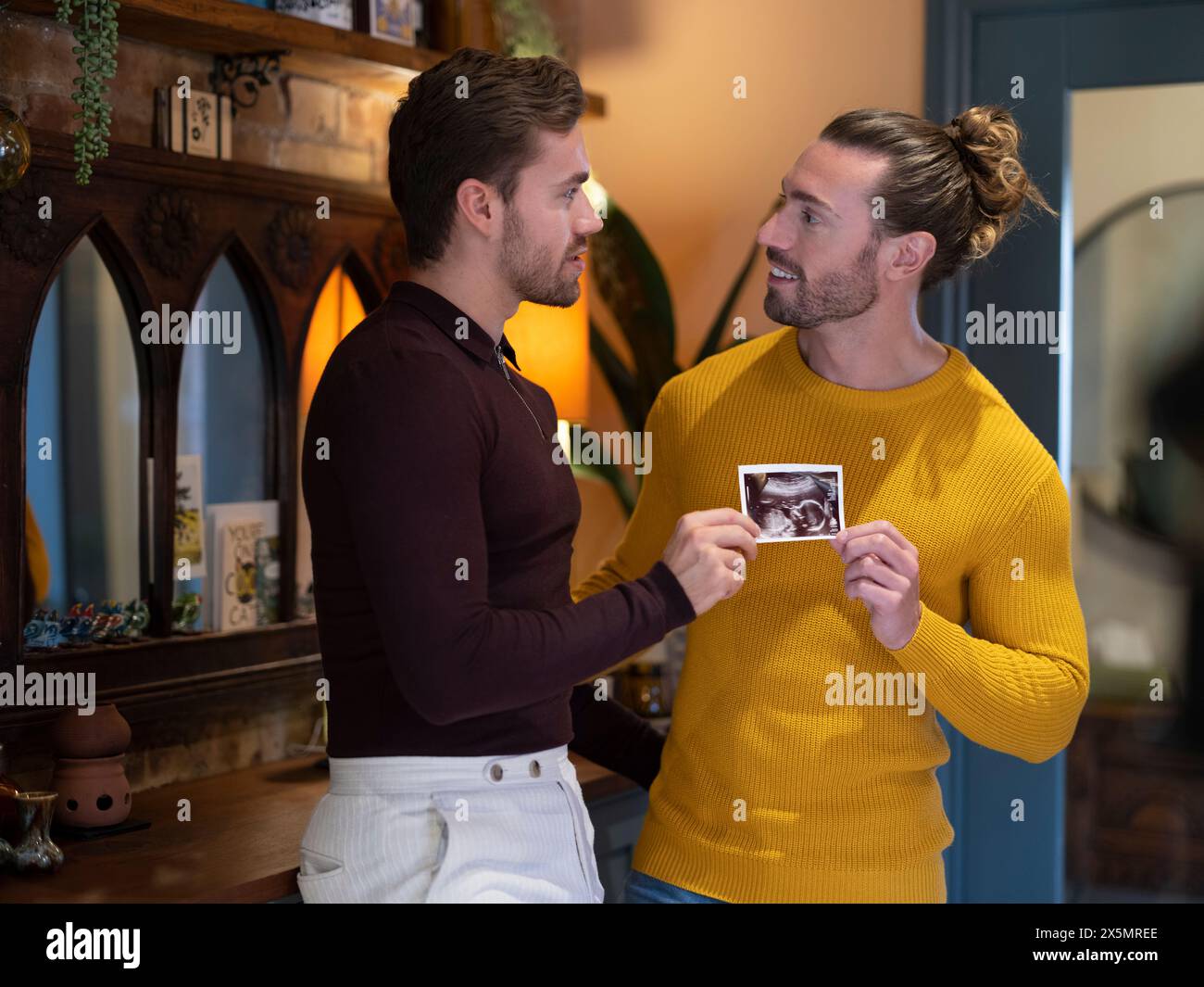 Schwulenpaar, das zu Hause Ultraschalluntersuchungen zeigt Stockfoto