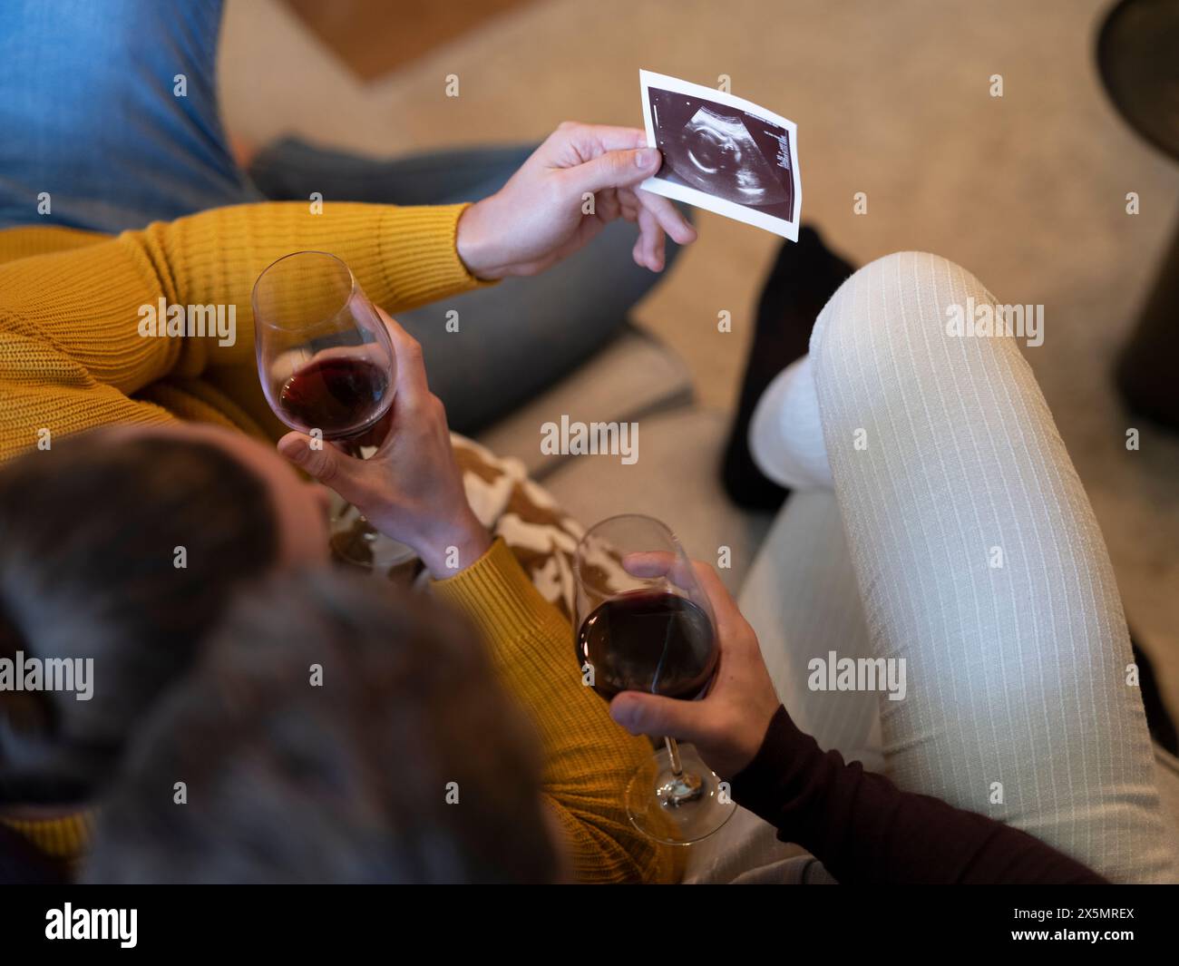 Schwulenpaar, das Ultraschall beim Trinken von Rotwein hält Stockfoto