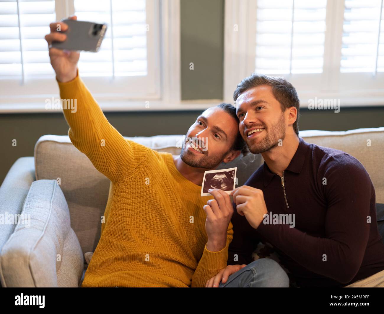Stolz schwules Paar, das zu Hause Selfie mit Ultraschall-Scan macht Stockfoto