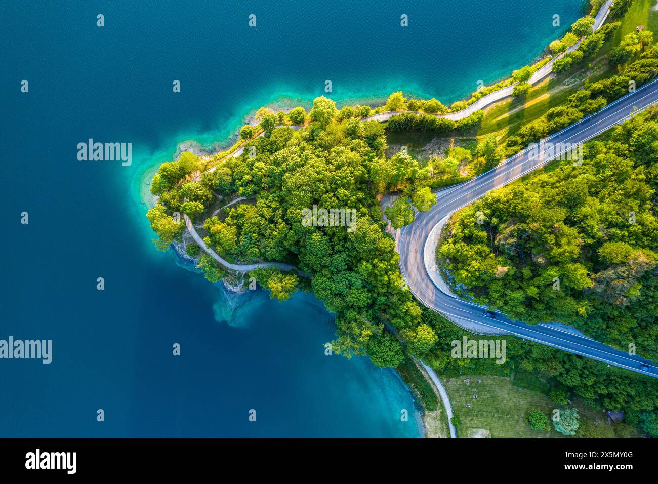 Blick aus der Vogelperspektive auf den Lago di Ledro mit türkisfarbenem Wasser und gewundener Straße, lebhafte Sommerlandschaft in Norditalien, malerische Seeroute Stockfoto