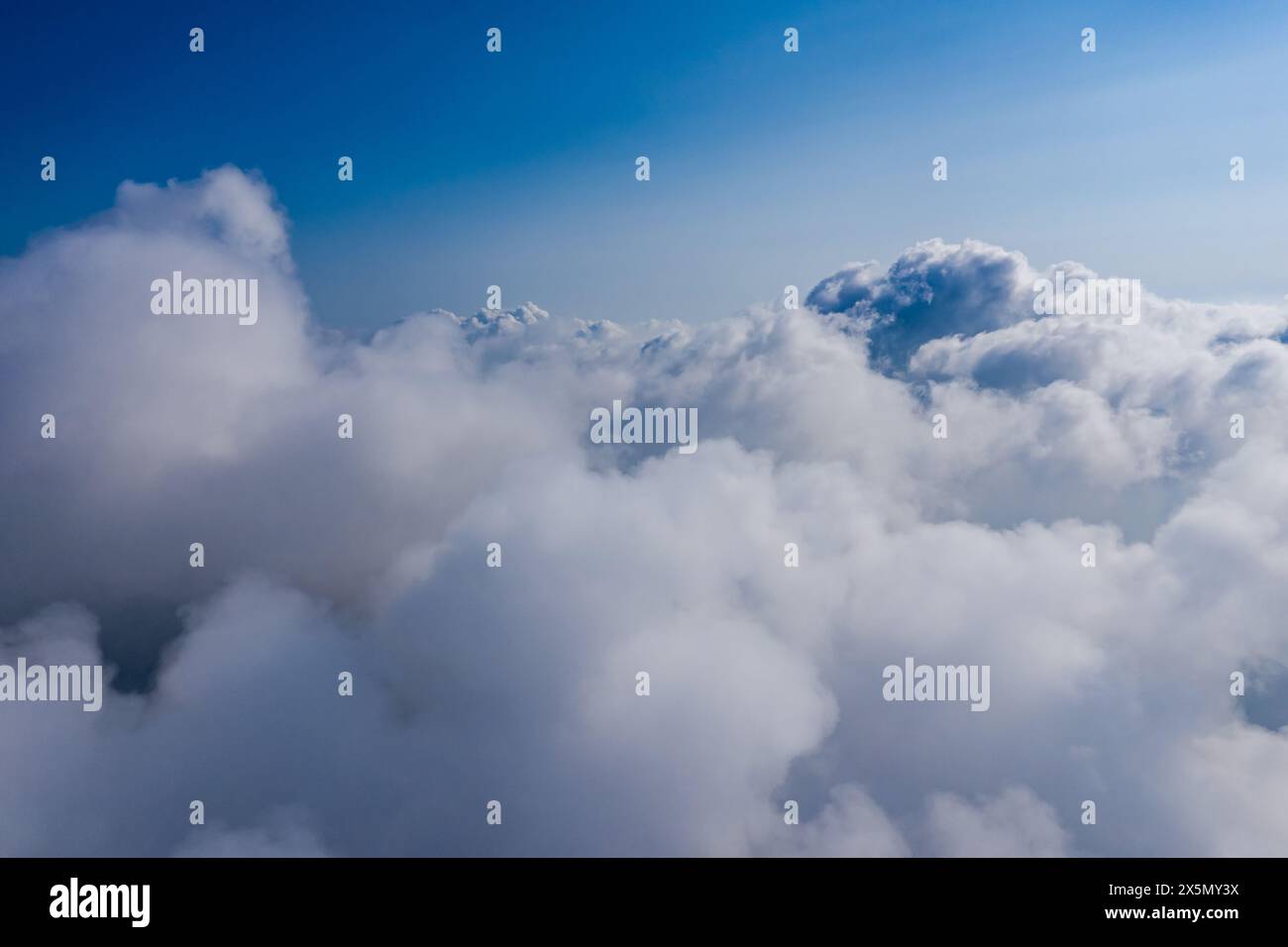 Aus der Vogelperspektive die flauschige Wolkenlandschaft, den ruhigen blauen Himmel und die Cumulus-Wolken aus großer Höhe Stockfoto