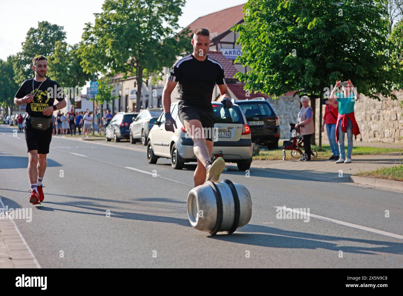 Ballenstedt, Deutschland. Mai 2024. Frank Kranich rollt ein Fass von Hoym nach Badeborn. Zum Ausgangspunkt. Die traditionelle Fassrolle von Hoym nach Badeborn wurde wieder in der kleinen Stadt abgehalten. Ein Teilnehmer aus Badeborn muss mit einem Fass eine Distanz von fast 6 Kilometern zurücklegen. Der Fass ist mit Wasser gefüllt und wiegt 60 kg. Frank Kranich entschied sich, dieses Jahr teilzunehmen. Er trainierte acht Wochen lang. Die 39. Walzenrolle stammt von einer Wette aus dem Jahr 1984, als erstmals ein Walzenfass von Hoym nach Badeborn gerollt wurde. Quelle: Matthias Bein/dpa/Alamy Live News Stockfoto