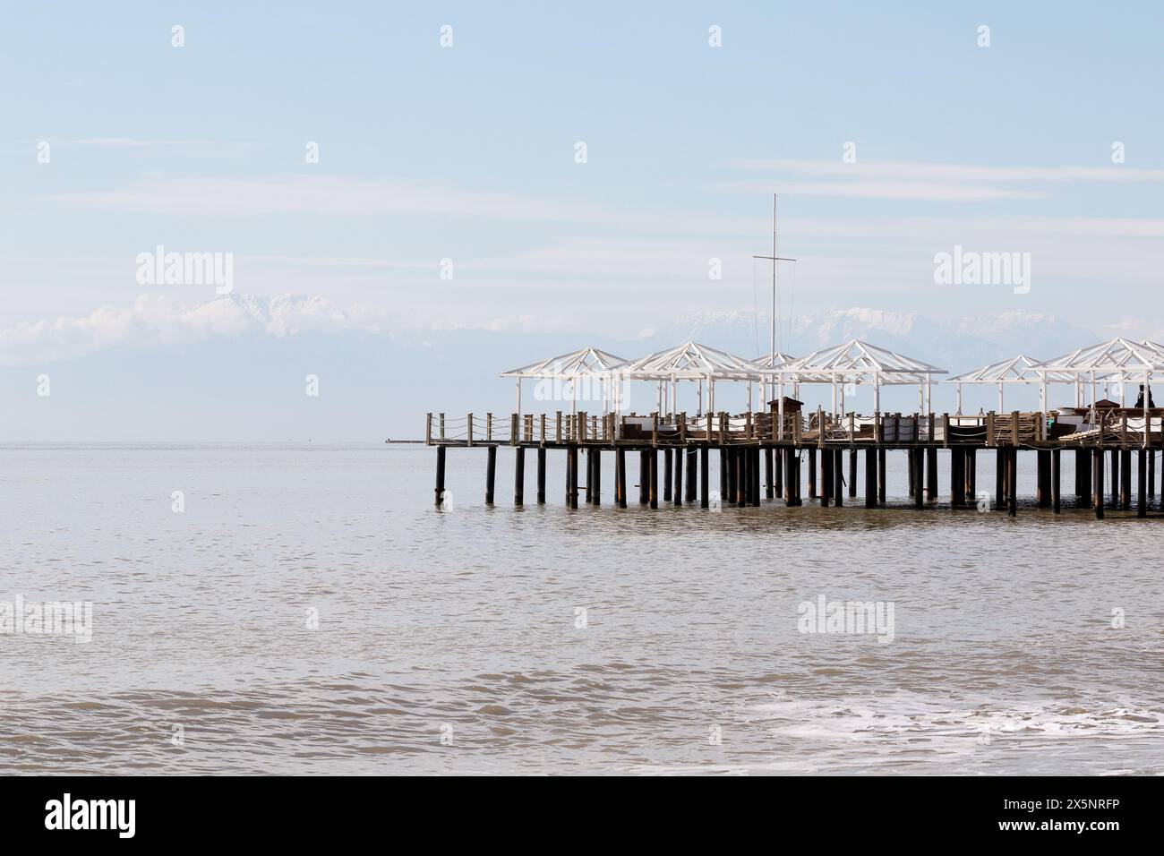 Uferdamm in der Türkei. Schneebedeckte Berggipfel am Horizont im Dunst Stockfoto