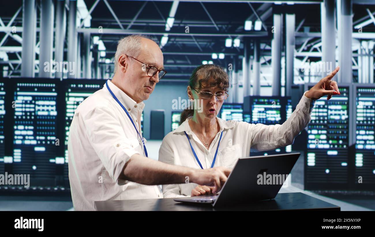 Kompetente Mitarbeiter, die sich in High-Tech-Rechenzentren umsehen, mit Laptops Disaster Recovery-Pläne abgleichen und Server-Gadgets bewerten, die ausgetauscht werden müssen, um Fehler zu vermeiden Stockfoto