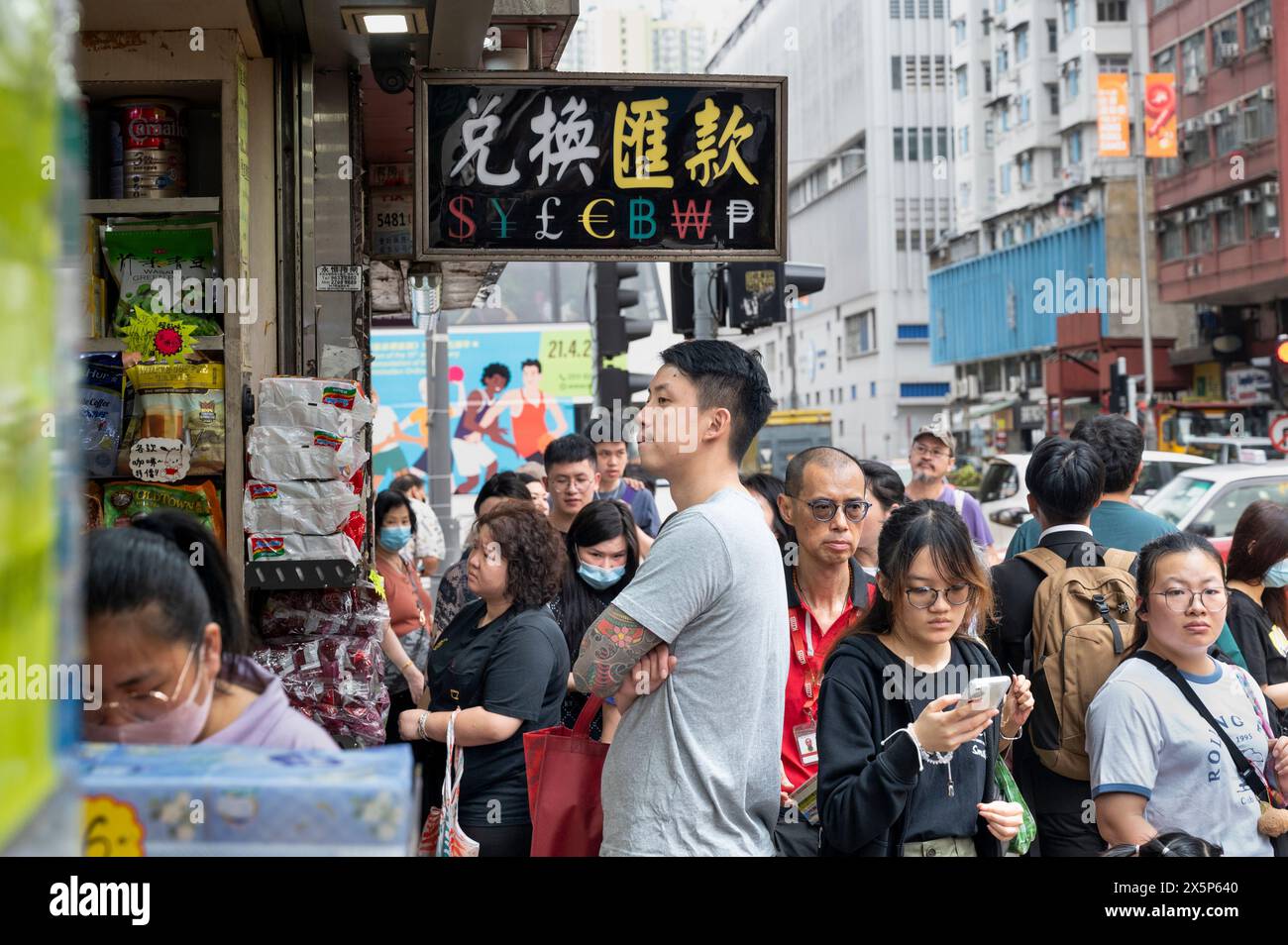 Fußgänger gehen an einer Geldwechselstube vorbei, auf der ein Schild steht: US Dollar ($), Japanischer Yen (¥), Britisches Pfund (£), Euro (€), Bitcoin (BTC, BCH), koreanischer Won und philippinischer Peso in Hongkong. Stockfoto