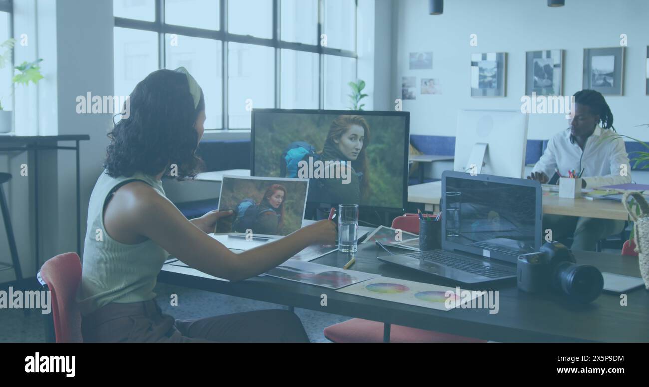 Biracial Pro prüft Fotos; afroamerikanischer Peer arbeitet in der Nähe Stockfoto