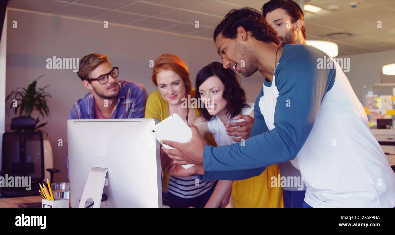 Freunde, einschließlich kaukasischer und birassischer Kollegen, schauen sich einen Computer an Stockfoto