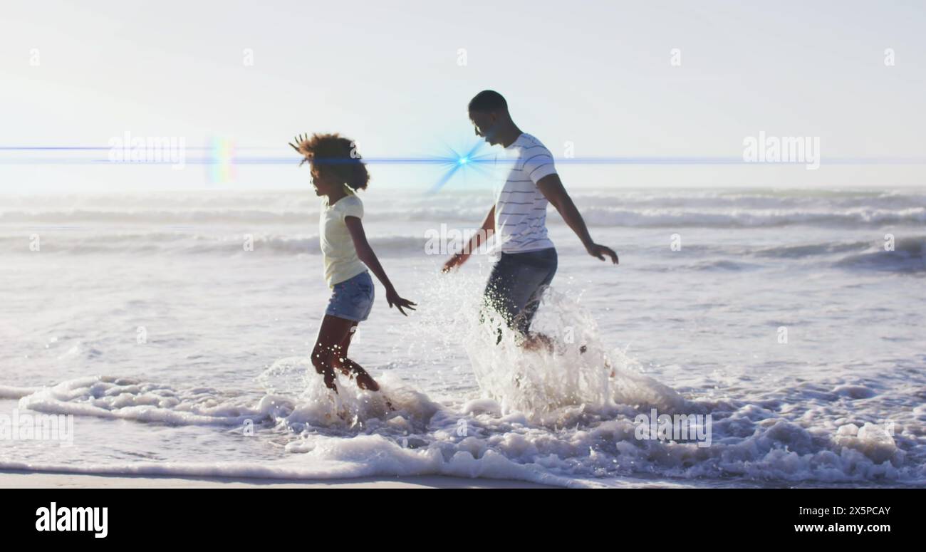 Bild von Lichtspuren über afroamerikaner und seine Tochter am Strand Stockfoto