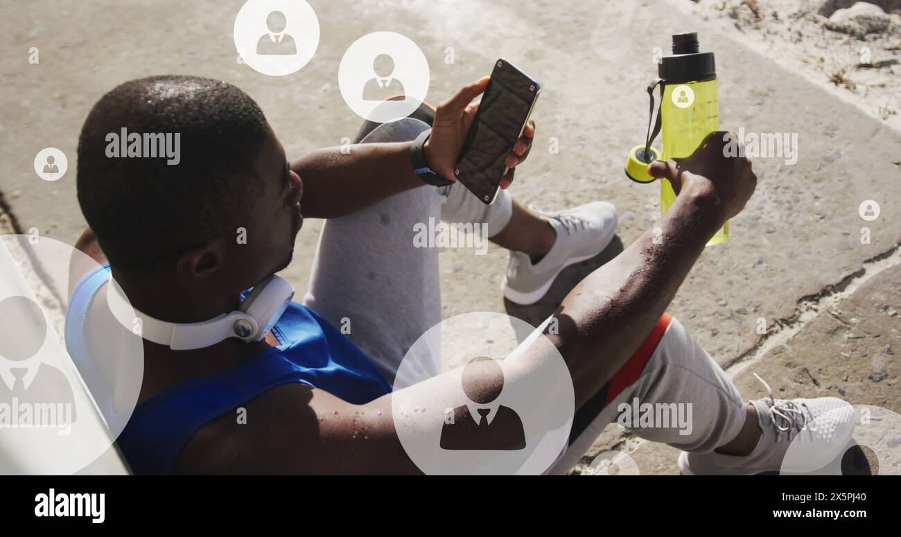 Bild von Profilsymbolen über müden afroamerikanischen Athleten, die sitzen und auf das Smartphone schauen Stockfoto