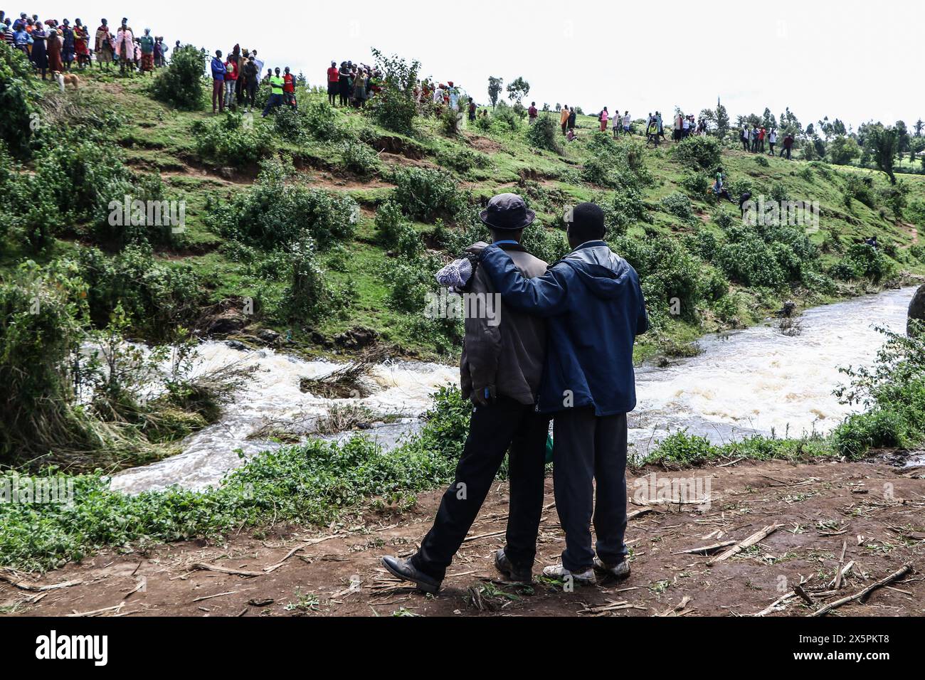 Nakuru, Kenia. Mai 2024. Mitglieder der Gemeinde beobachten, wie einheimische Taucher nach Leichen von zwei jungen Schwestern suchen, die ertrunken sind, als sie versuchten, einen geschwollenen Njoro River in Ketiro Village, Nakuru County, zu überqueren. Ihr tragischer Tod erhöht die Zahl von mindestens 230 Menschen, die nach starken Regenfällen, die in Kenia zu großen Überschwemmungen geführt haben, ihr Leben verloren haben. Quelle: SOPA Images Limited/Alamy Live News Stockfoto