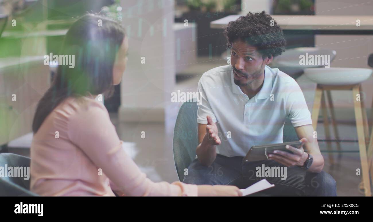 Ein vielseitiges Paar diskutiert, ein Mann hält ein Tablet Stockfoto