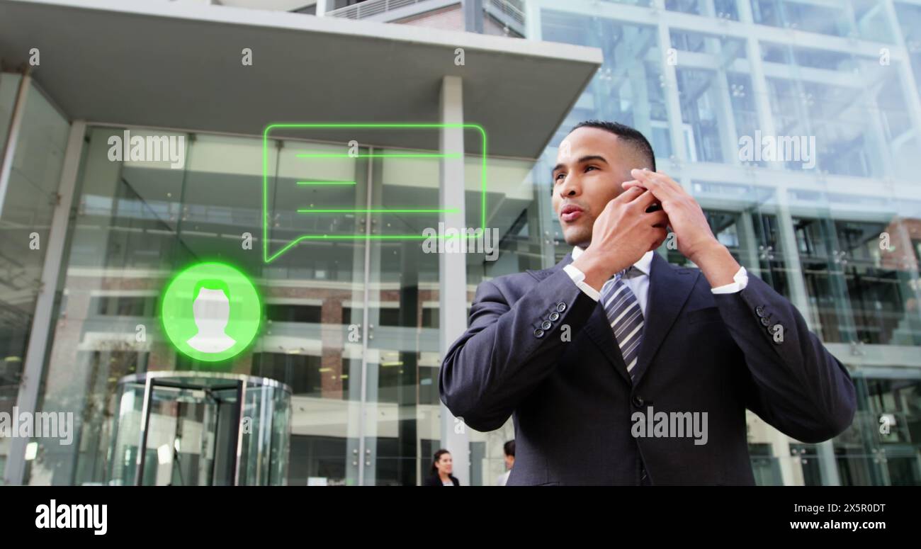 Ein junger, birassischer Mann im Anzug, der auf einem Smartphone vor dem Bürogebäude spricht Stockfoto