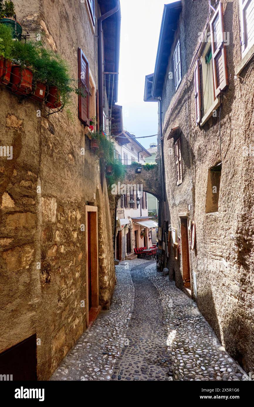 Malerische Kopfsteinpflasterstraße mit historischen Steinhäusern und Blumenkästen in einem charmanten italienischen Dorf Stockfoto