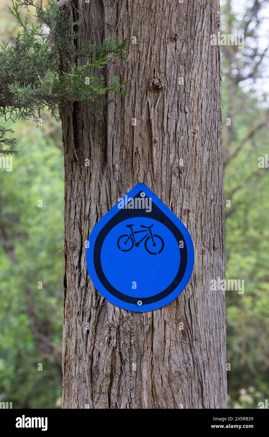 Baumstamm mit blauem Schild für Fahrradrouten Stockfoto
