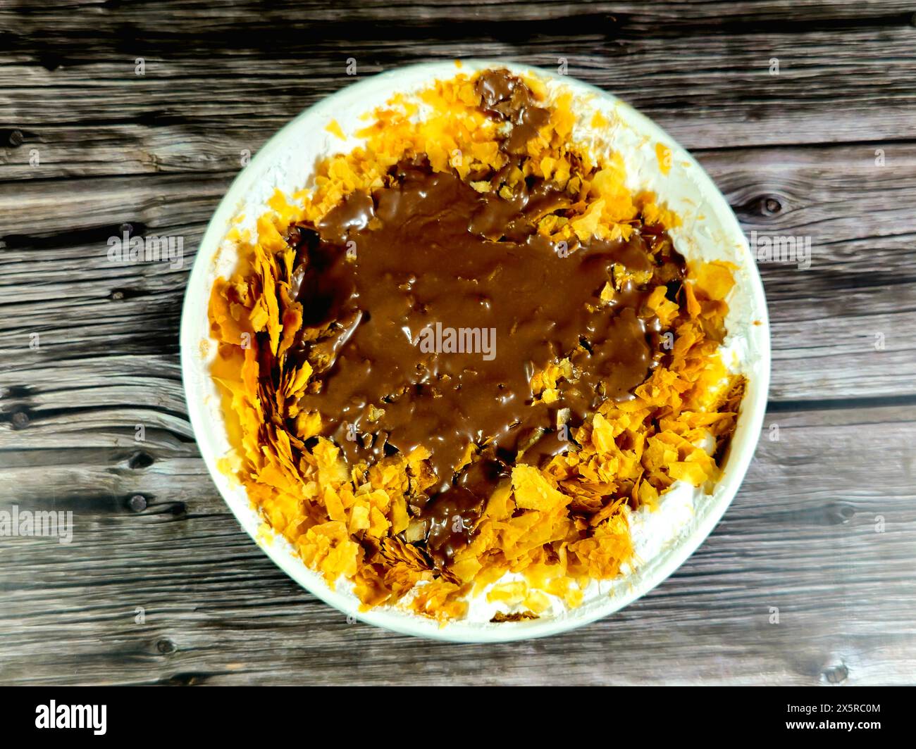 Schokoladenpaste Sauce auf dem süßen Koshary Rezept in Ägypten aus mehreren Schichten Reis mit süßem Milchpudding, Schlagsahne, geröstetem Konafa und Stockfoto