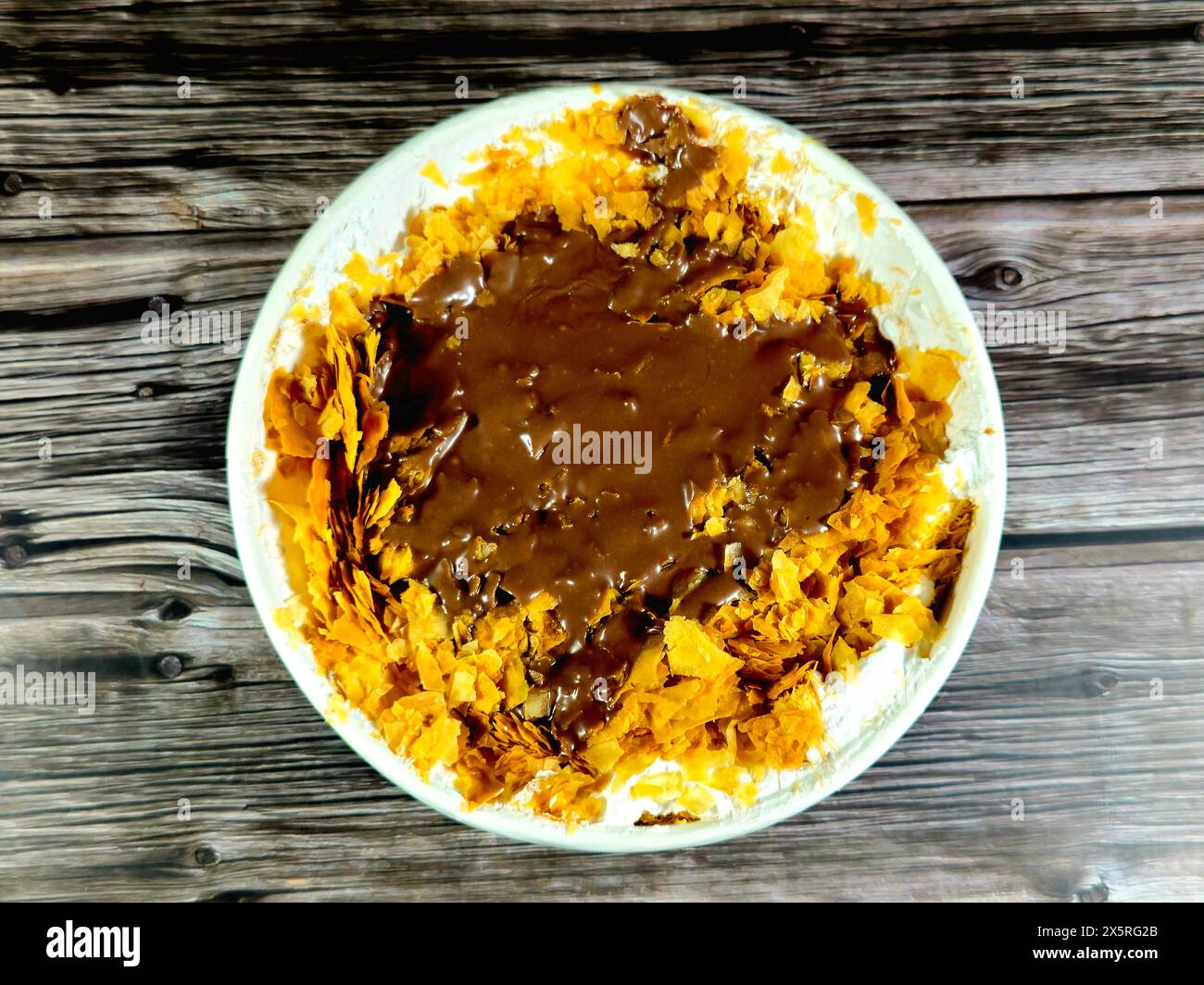 Schokoladenpaste Sauce auf dem süßen Koshary Rezept in Ägypten aus mehreren Schichten Reis mit süßem Milchpudding, Schlagsahne, geröstetem Konafa und Stockfoto