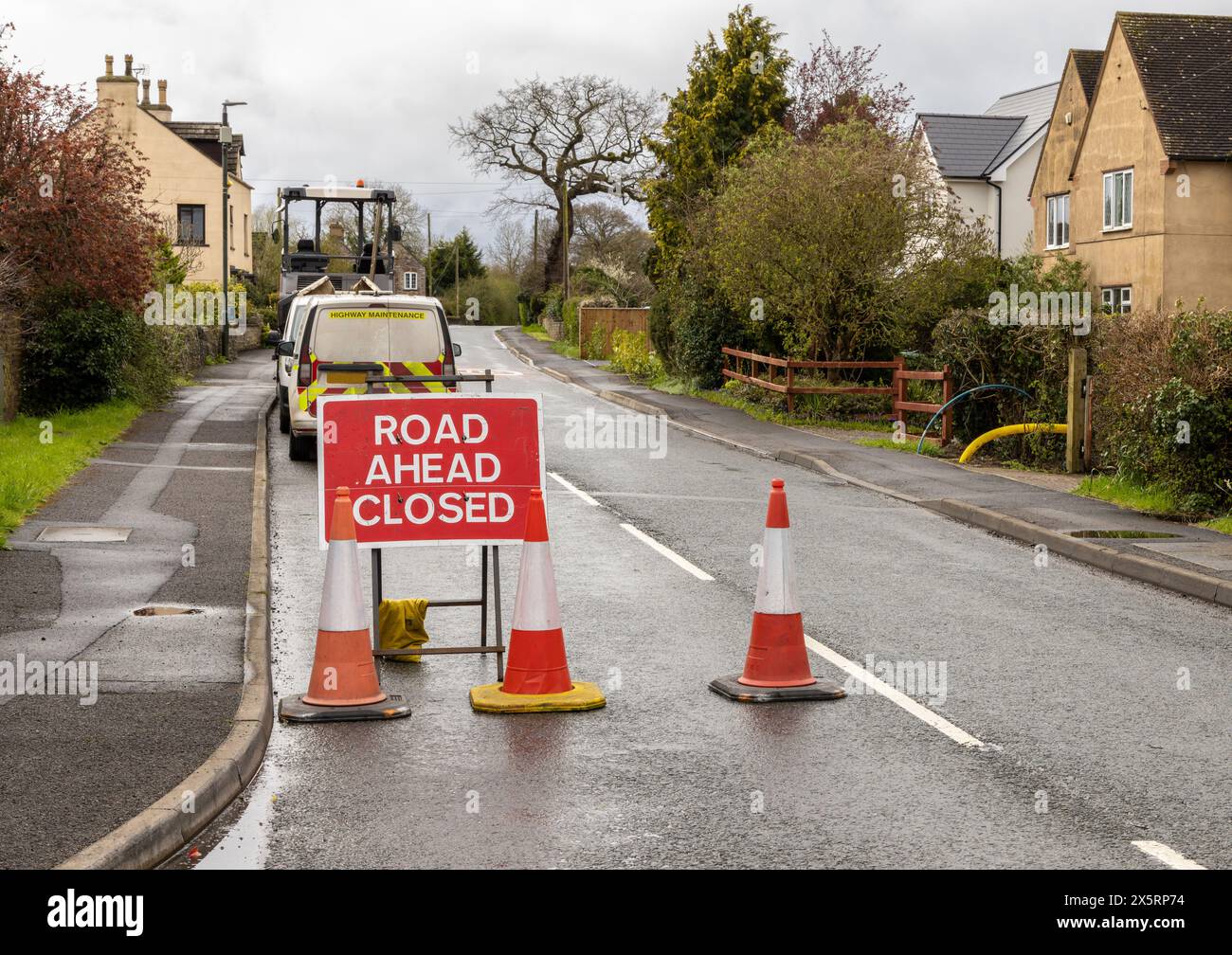 Schild „Road Ahead Closed“ (Straße vor geschlossen) mit Highway Maintenance-Van – Metallweiß auf rotem Text Stockfoto