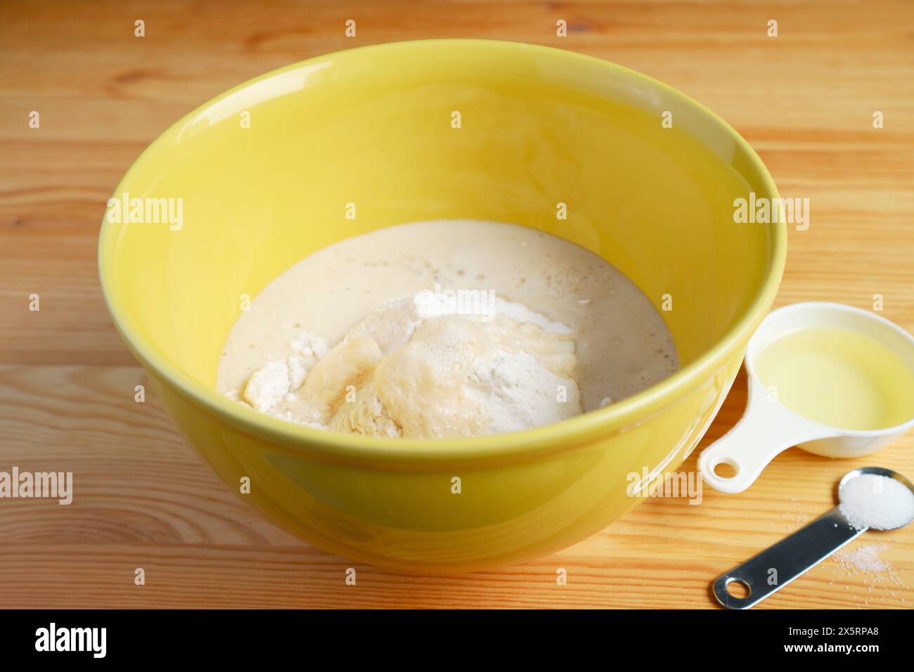 Mischen Sie eine Schüssel mit Mehl und Hefe, um Brotteig zu machen Stockfoto
